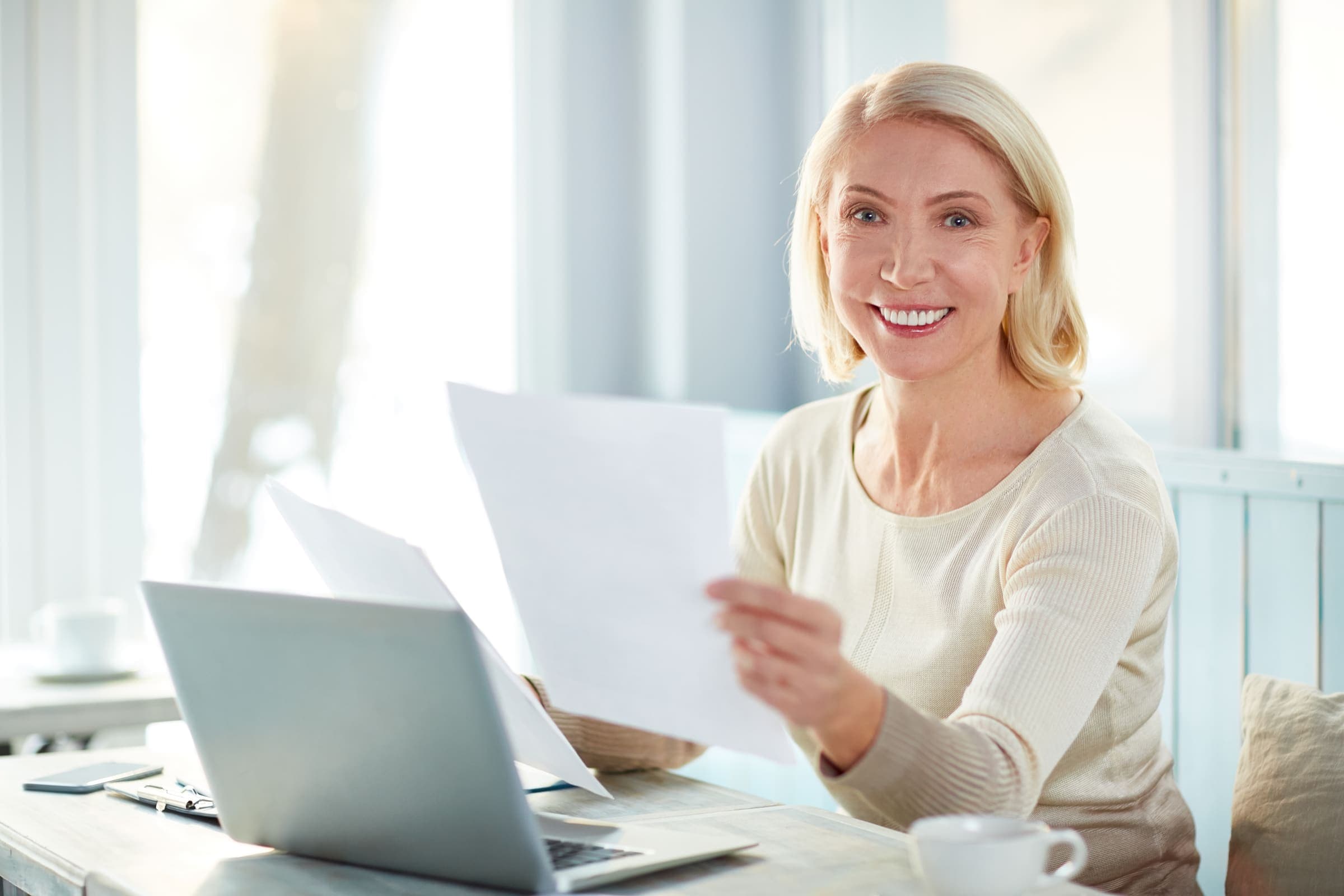 Consulente CAF che assiste con il sorriso, tra documenti e laptop